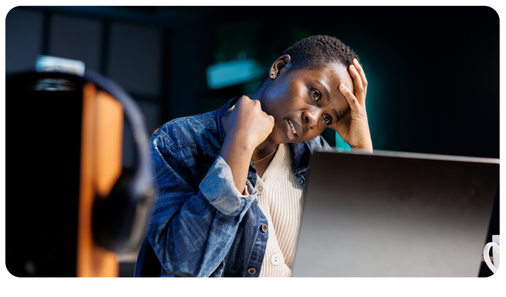 Woman holding her head looking at a laptop screen
