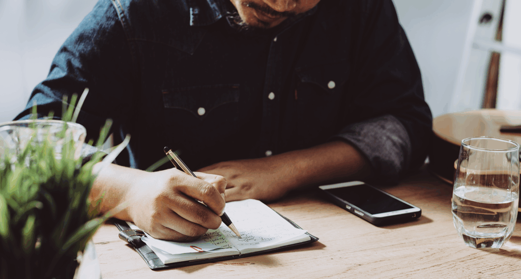 man writing in a journal