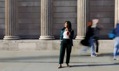 woman standing in front of a building holding a cell phone