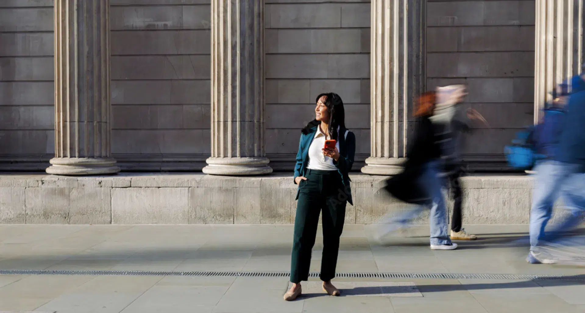woman standing in front of a building holding a cell phone