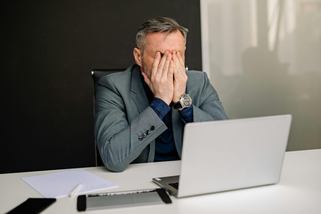 man frustrated sitting in front of a laptop